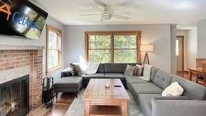 A living room with a fireplace, a sofa set, a coffee table, and a television mounted on the wall. - Hidden Kingdom | Near Echo Lake, Private Retreat w/ Outdoor Space (Plymouth)