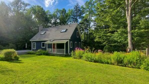 A house with a sloped roof, a porch, and a well-maintained lawn.