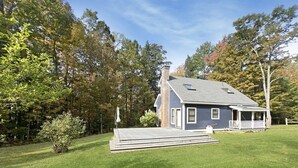 A house with a covered patio, a chimney, and a well-maintained lawn.