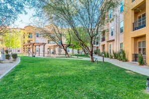 A courtyard with a well-maintained lawn, pergola structures, and multi-story buildings with balconies. - Surprise Goodie! Ground Floor, Garage 30 night min (Surprise)