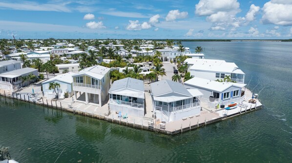 A waterfront property with multiple houses, a dock, and a clear view of the ocean.