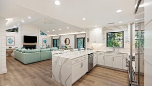 A modern kitchen with a marble island, white cabinetry, and a built-in oven. - KIAWAH, West Beach, 5BR Luxury Home, POOL & Incredible PORCHES! (Kiawah Island)