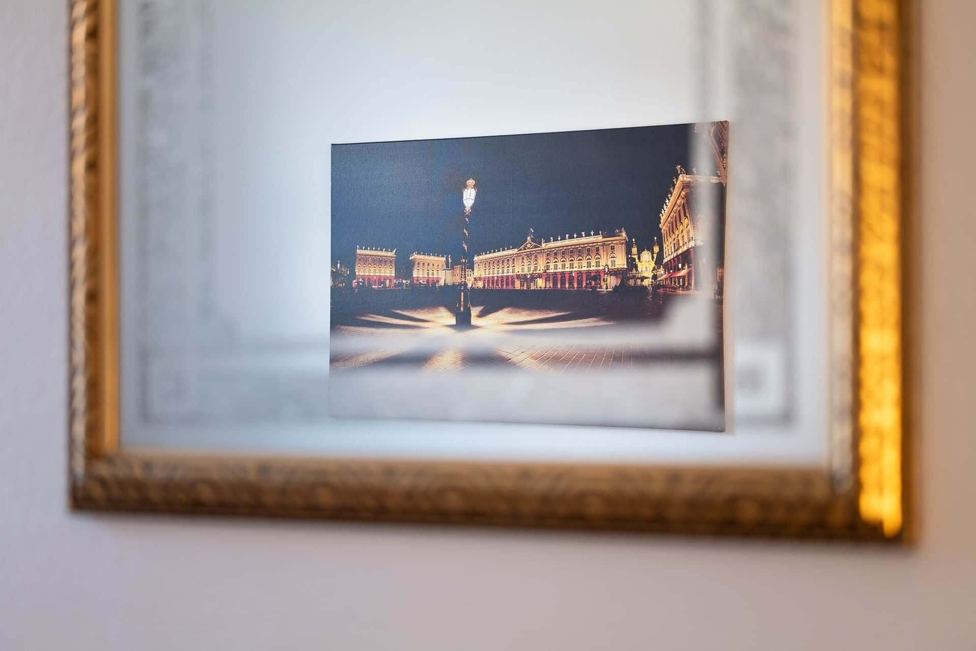 Une photographie encadrée représentant un bâtiment avec une fontaine au premier plan.