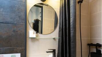 Un baño con lavamanos, espejo y ducha.
