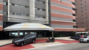 A modern building with a covered entrance, a grey SUV, and a motorcycle parked in front. - Hosts BR - Flat Vista Mar no Meireles (Fortaleza)