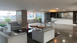 A modern lobby with a seating area, a reception desk, and a view of the outside. - Hosts BR - Flat Vista Mar no Meireles (Fortaleza)