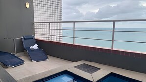 A pool area with two lounge chairs and a view of the sea. - Hosts BR - Flat Vista Mar no Meireles (Fortaleza)