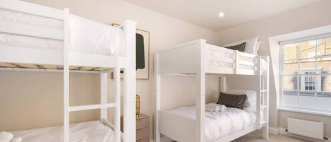 A room with bunk beds, a small bedside table, a radiator, and a window with a view.