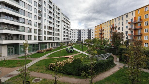 Een modern appartementencomplex met meerdere gebouwen, een centrale binnentuin met beplanting en een verzorgd gazon.