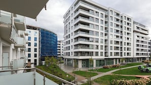 Een modern appartementencomplex met meerdere balkons en een aangelegde tuin.