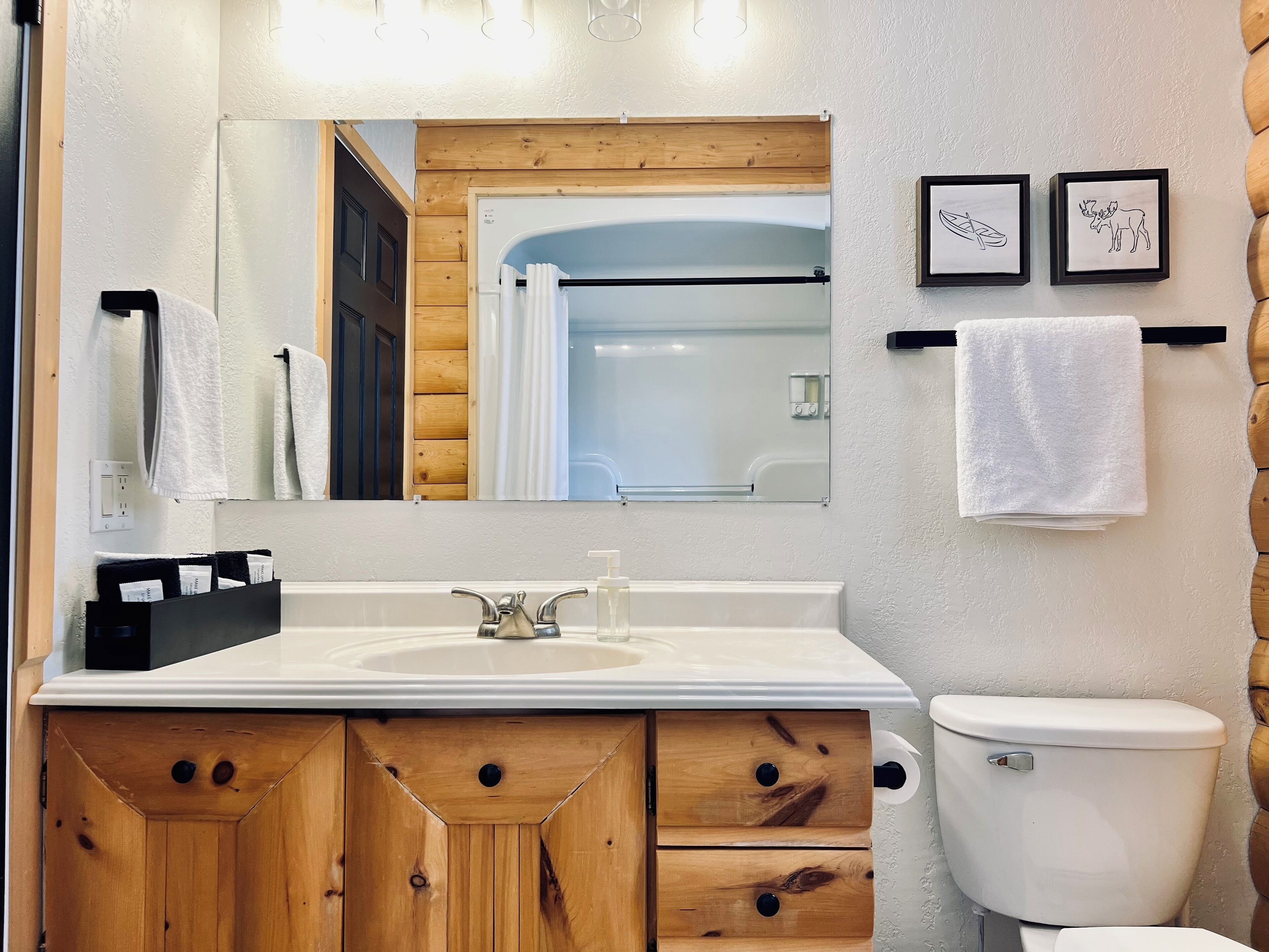 Une salle de bain avec des meubles en bois, un lavabo blanc, un miroir et des toilettes.