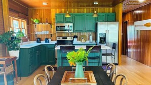A spacious kitchen with wooden cabinets, a dining table, and chairs. - Smokey Hollow Motel & Resort (Onanole)