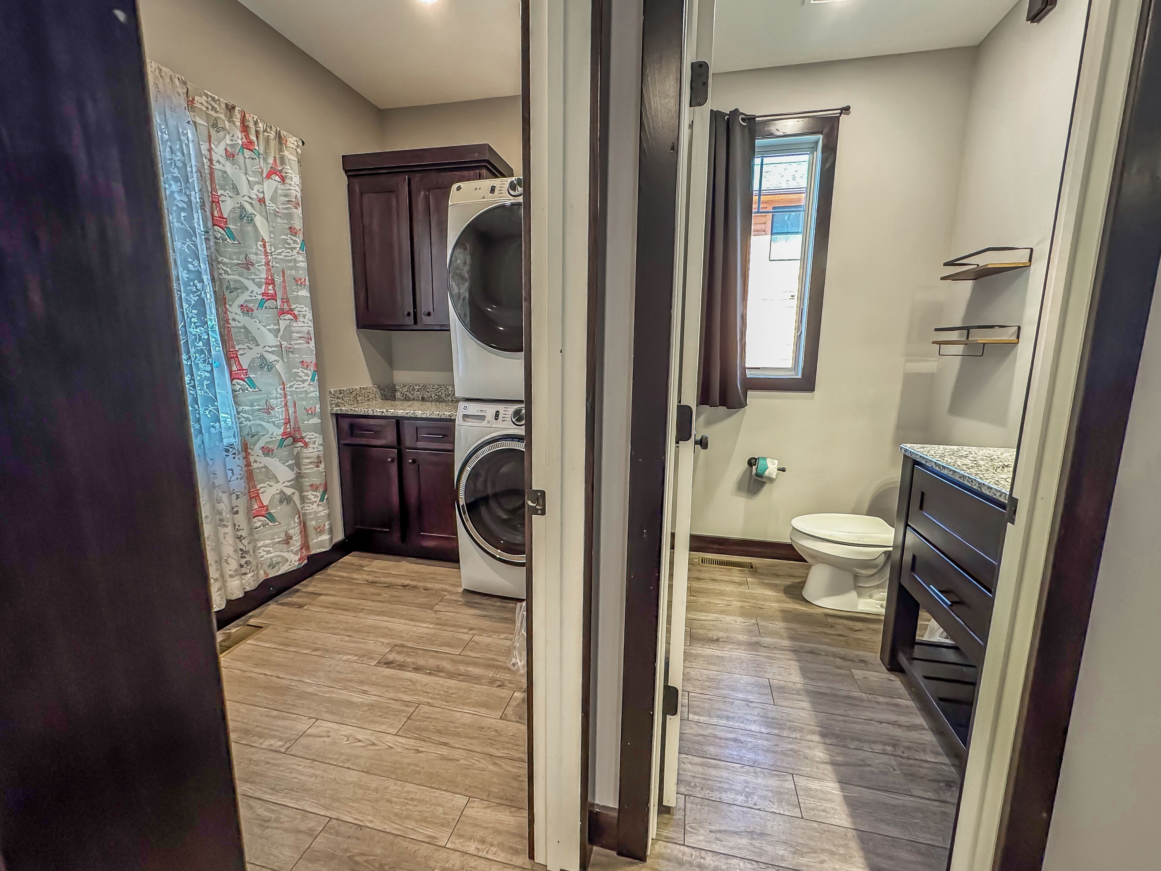 A laundry room with a washing machine, a dryer, and a window with curtains.