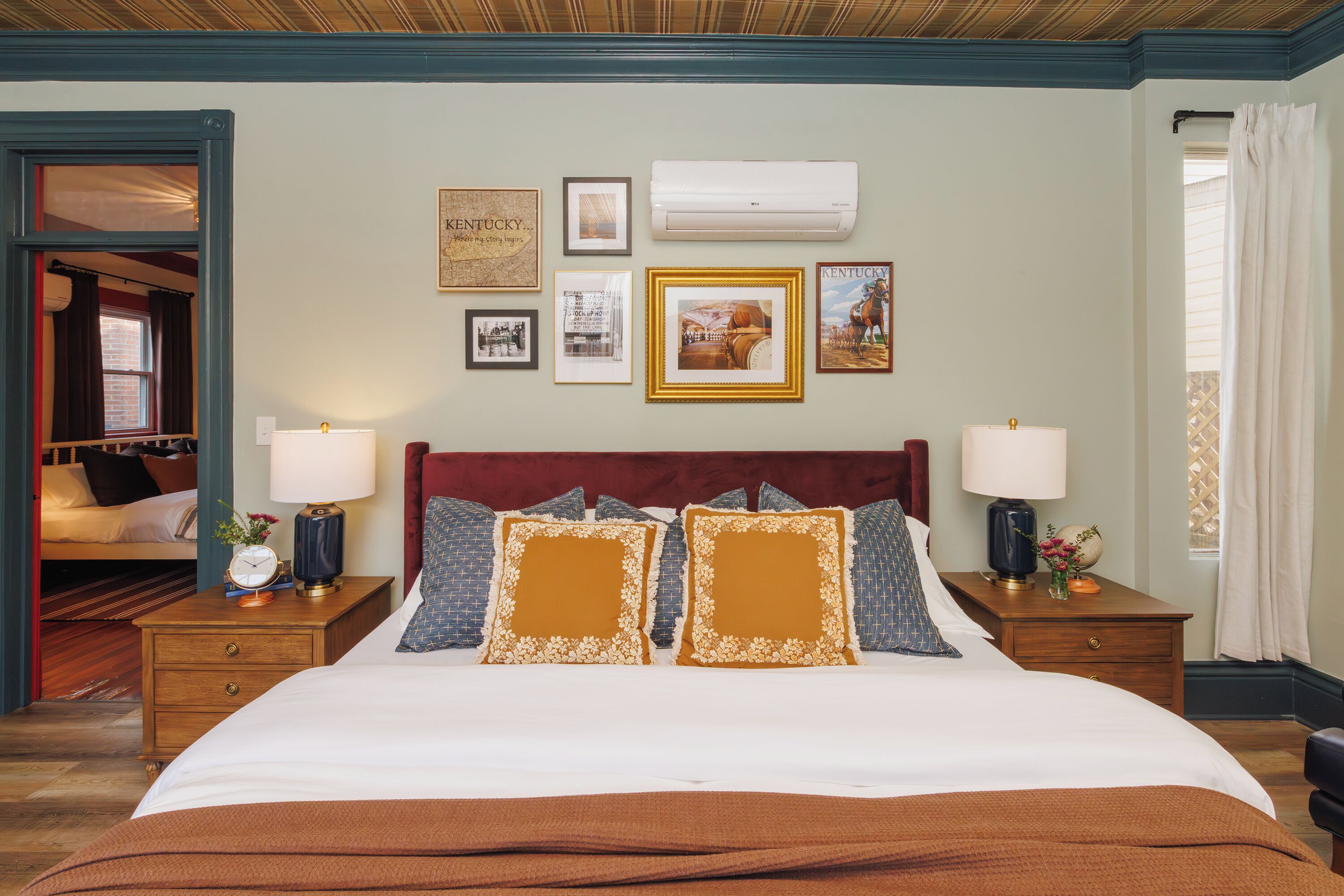 A hotel room with a large bed, two nightstands, a wall-mounted air conditioner, and framed pictures on the wall.