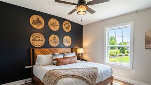 Een slaapkamer met een houten hoofdbord, een groot raam en wanddecoratie.