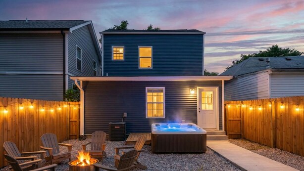 Een achtertuin met een jacuzzi, houten stoelen en lichtjes.
