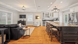 A modern kitchen with a central island, dark cabinetry, and stainless steel appliances. - Bourbon Trail Estate | 3 Epic Acres | 7 Bed 6 Bath (Louisville)