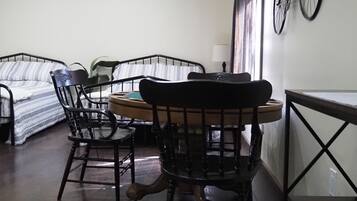 A compact room with a bed, a dining table with chairs, and a bicycle mounted on the wall.