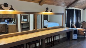 Um longo balcão de madeira com um espelho refletindo um quarto e uma cadeira.
