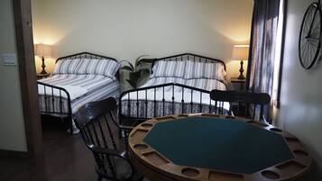 A room with two beds, a round table with chairs, a lamp, and a bicycle mounted on the wall.