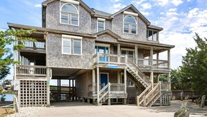 Une maison en bois à plusieurs étages, dotée d’un balcon, d’un escalier et d’une jetée qui s’avance dans l’eau.