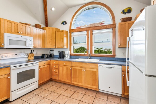 A kitchen with wooden cabinets, a white refrigerator, a microwave, a stove, and a sink.