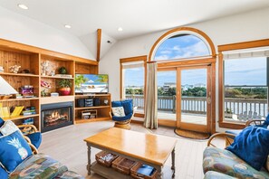 A cozy living room with a fireplace, wooden shelves, and a large TV.