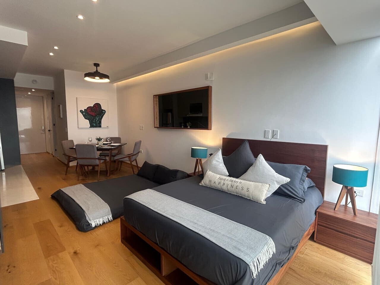 A modern bedroom with a large bed, bedside tables, a desk, and a chair.