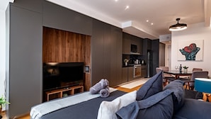 En moderne stue med et stort fladskærms-tv, en sofa og et spiseområde med et bord og stole.