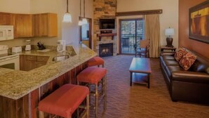 Habitación de hotel con cocina, mesa de comedor, sofá y chimenea.
