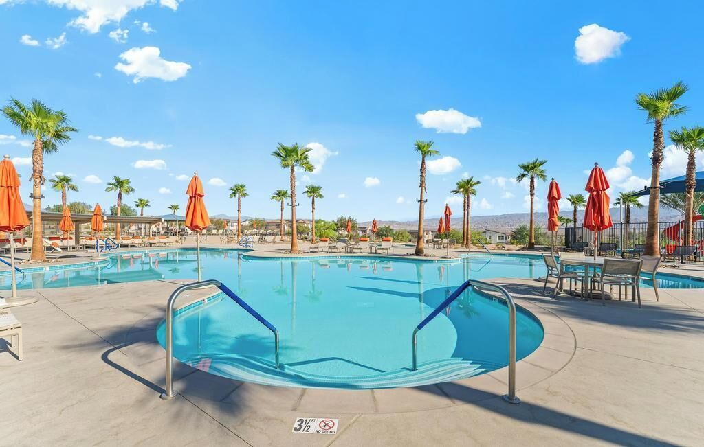 A pool area with multiple swimming pools, palm trees, and orange umbrellas.