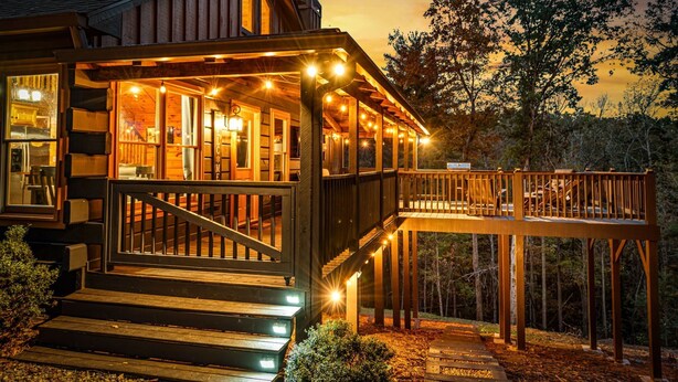 A wooden cabin with a deck and a covered porch, surrounded by trees. - Narcoossee Ridge -  NEW, Hot Tub, Views, Arcade and Airhockey (Mineral Bluff)