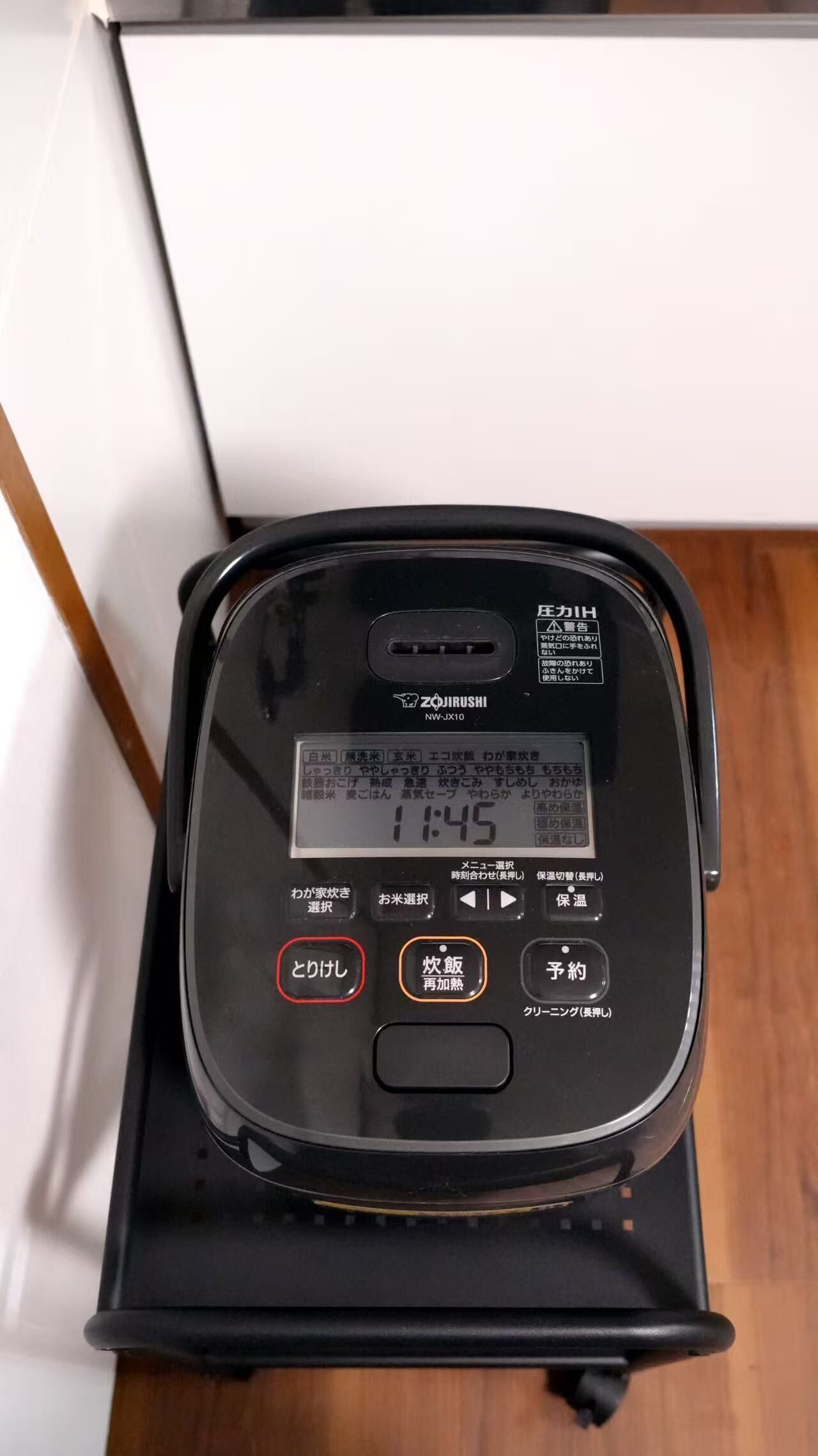 A black rice cooker with a digital display, buttons for various functions, and a brand name visible.