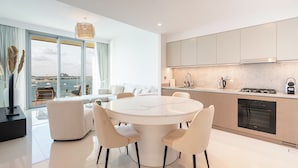 Una cocina moderna con una mesa de comedor redonda, armarios blancos y vistas al mar.