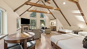 A spacious loft bedroom with a large bed, a wooden ceiling, a fireplace, and a TV. - Augusta 3 - Private Heated Pool - Sweeping Golf Course Views - Separate Apartment (Sunriver)