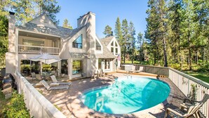 Une maison à deux étages avec une piscine, du mobilier d’extérieur et une terrasse.