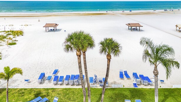 A beach with white sand, blue lounge chairs, and palm trees. - Plunge into Joy & Sun at Siesta Key Coastal Gem - Aloha Kai #60 (Siesta Key)