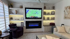 A living room with a fireplace, a television mounted on the wall, and a sofa. - Capital Cottage-Merrimon-Wynne, Garage, Walkable! (Raleigh)