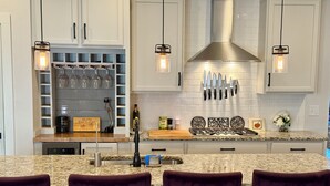 A kitchen with white cabinets, a granite countertop, and a central island with bar stools. - Capital Cottage-Merrimon-Wynne, Garage, Walkable! (Raleigh)