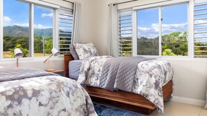 Une chambre avec deux lits, de grandes fenêtres et une vue sur la verdure.