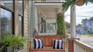 A porch with a wooden bench, potted plants, and hanging decorations.