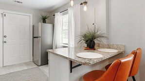 A kitchen with a granite countertop, two white plates, a potted plant, and a refrigerator.