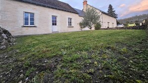 A stone building with a flat roof, a small lawn, and a tree in front.