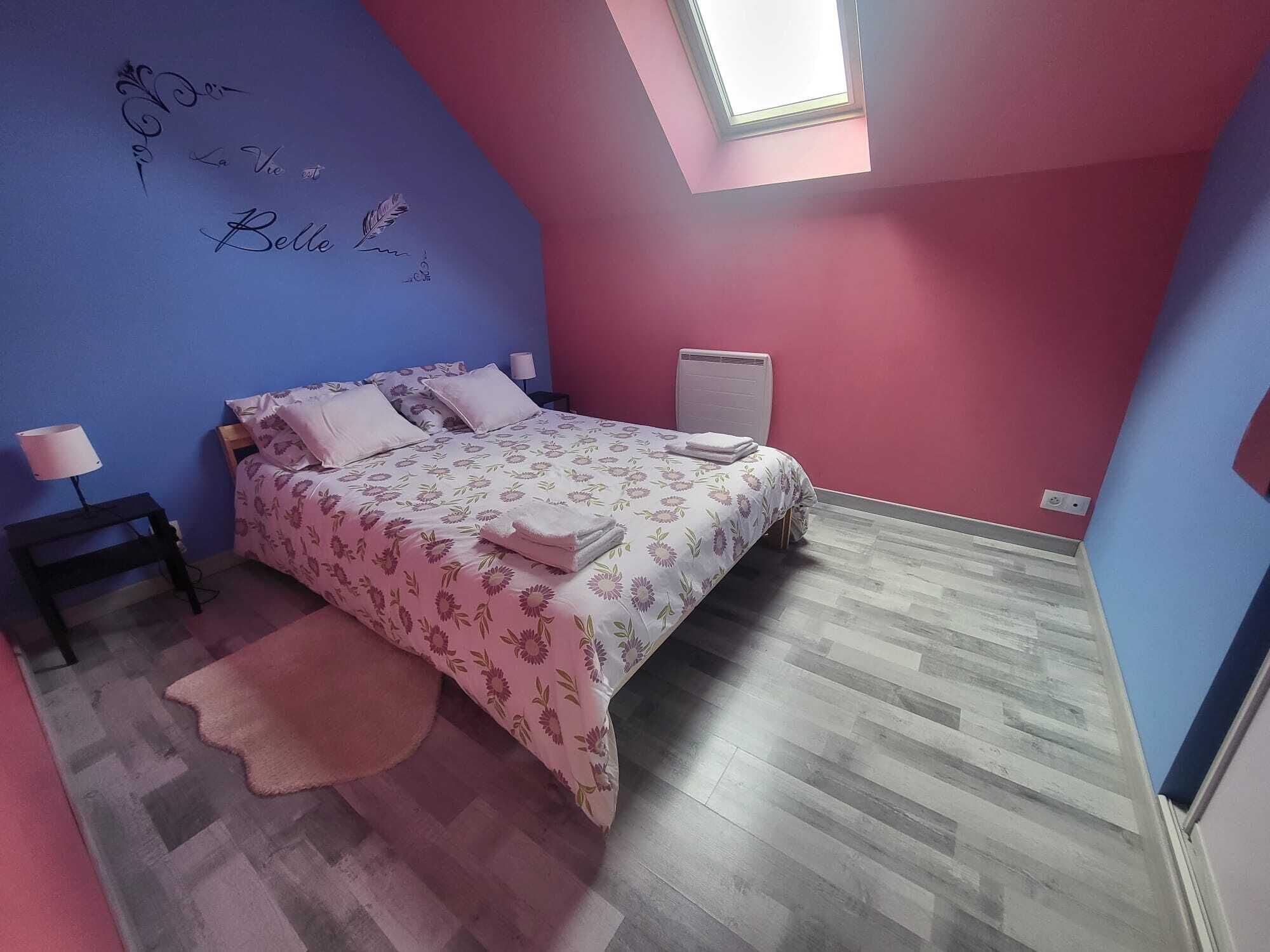 Un dormitorio con cama, mesita de noche, lámpara, radiador y tragaluz.
