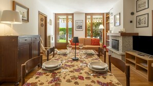 A dining area with a table set for four, a wooden cabinet, and a television on a stand. - Lovely apartment for 5 people with WIFI, TV and pets allowed (Bormio)