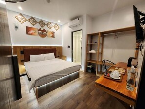A modern bedroom with a large bed, a wooden desk, and a built-in shelf. - Thành Nam Hotel (Dien Bien Phu)