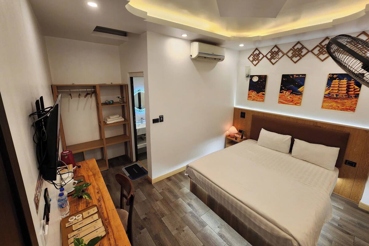 A hotel room with a bed, wooden furniture, a desk, and wall art.