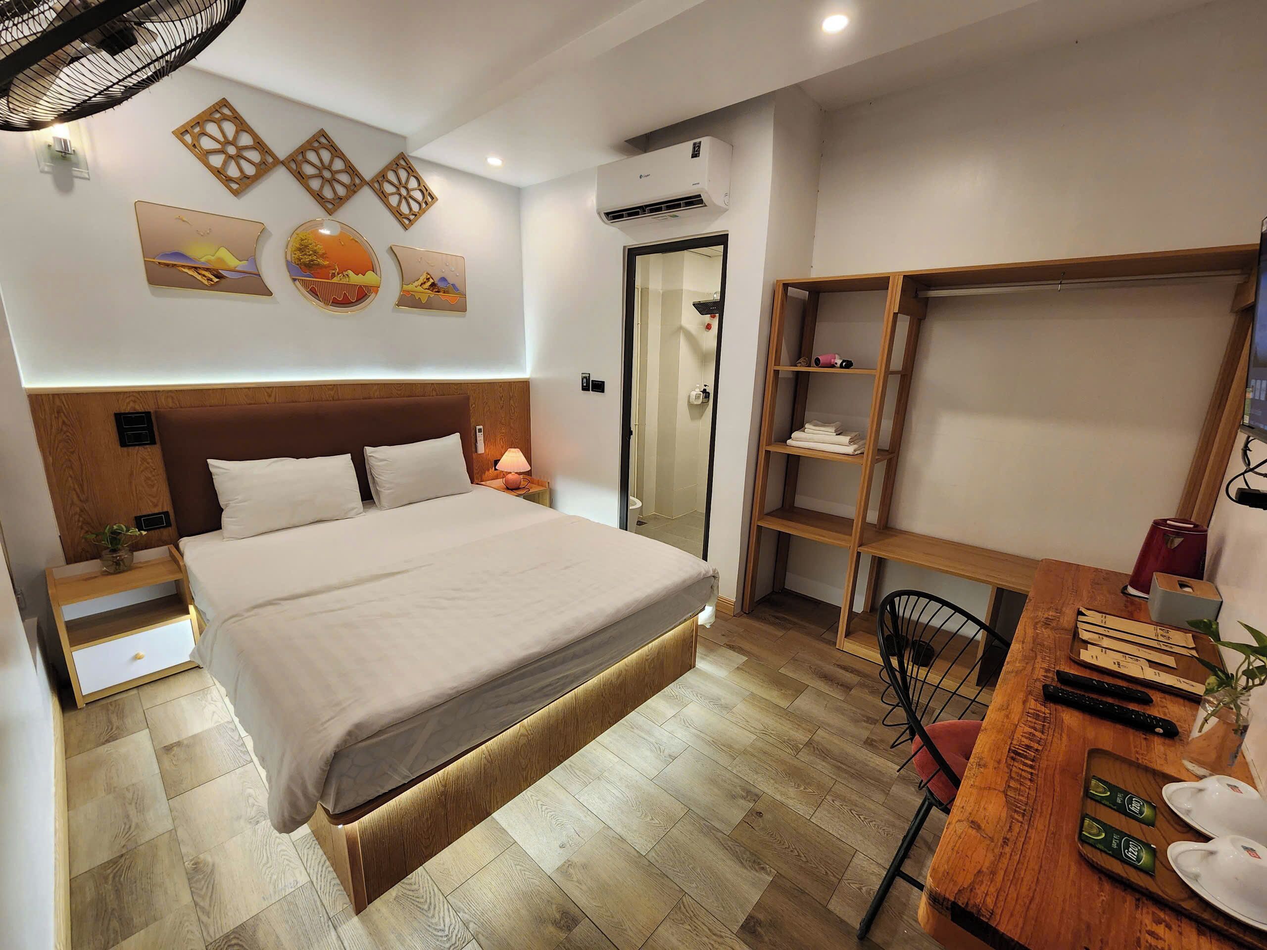 Ett modernt hotellrum med en stor säng, sängbord, ett skrivbord med en stol och en garderob.
