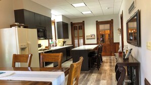 A compact kitchen with dark cabinetry, a central island, and a dining area with wooden chairs and a table.