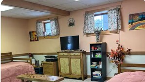 Een gezellige kamer met twee bedden, een houten tafel, een televisie en een boekenplank.